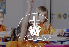 Student in orange shirt raises hand in classroom with a white cross and open book overlay.