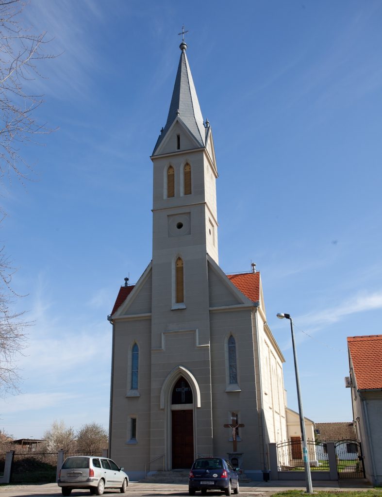 Church with a tall pointed steeple and cross against a bright blue sky