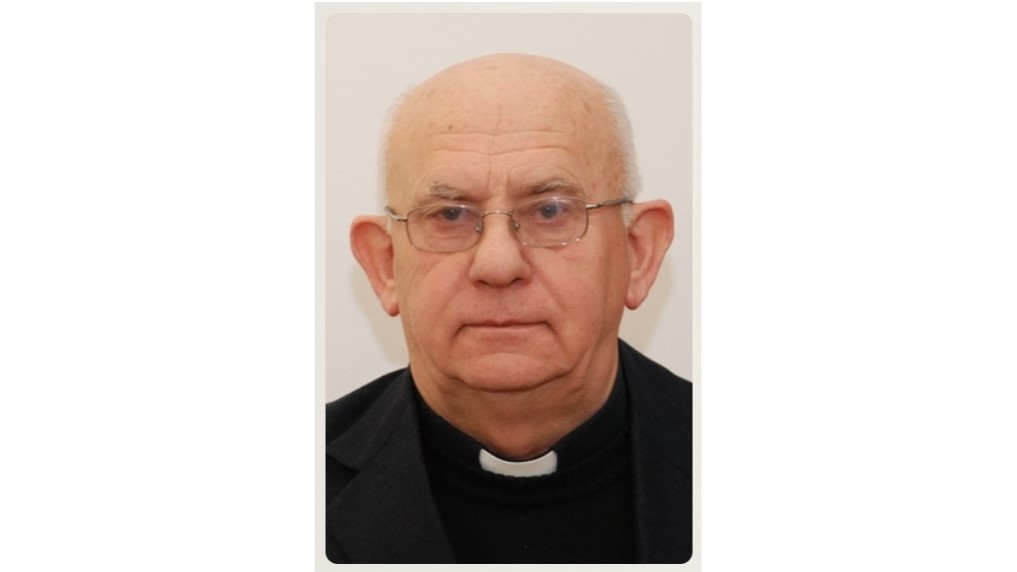 Portrait of an older man with glasses and a clerical collar facing the camera.