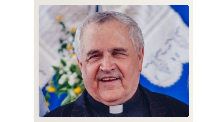 Portrait of a smiling Catholic priest wearing a clerical collar, facing the camera.