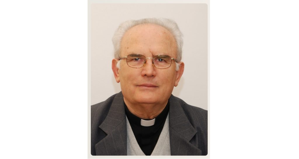 Head-and-shoulders portrait of an older man in a clerical collar and glasses, facing the camera.