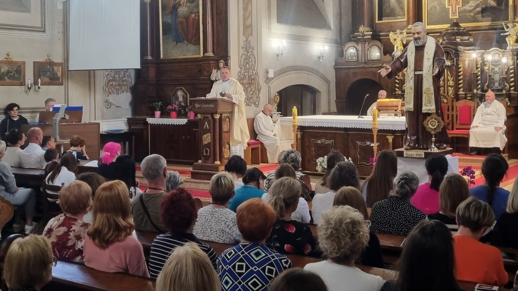 Priest delivering sermon at the pulpit in a richly decorated church with the congregation seated in pews nearby.