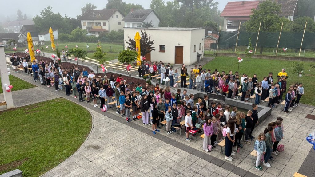 A large group of students lined up in rows outside a school courtyard for an assembly or ceremony.