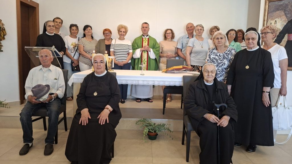 Group of clergy and parishioners posing behind an altar in a church during a blessing ceremony.