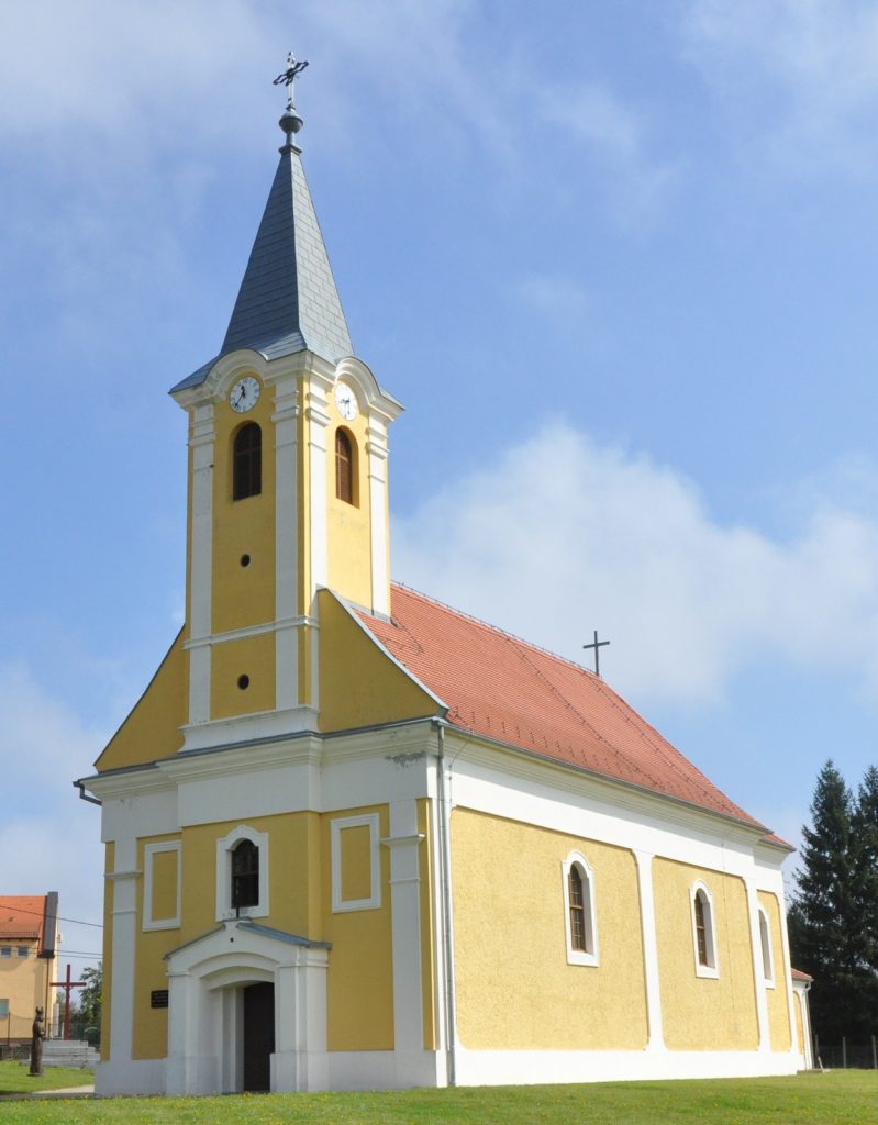 Yellow church with white trim, tall steeple, and clock tower set against a blue sky. (informative)